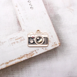 Macro shot of a vintage alloy camera charm with black and gold enamel details