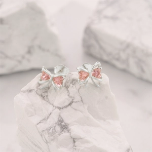 Detailed view of S925 silver bow stud earrings with pink heart-shaped crystal stones