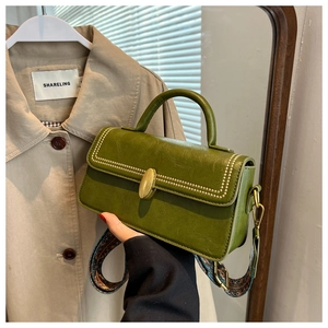 Detail of olive green leather handbag with gold hardware and bohemian printed strap