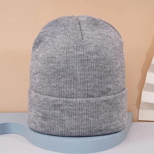 Gros plan d'un bonnet en tricot gris sur support bleu avec fond de couleur chaude