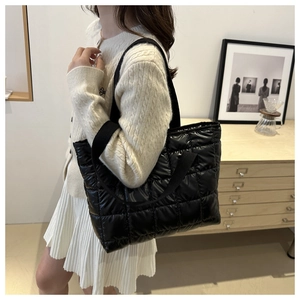 Quilted black puffer tote bag shown on model with cozy knitwear in a warm home setting