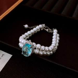 Détail d'un bracelet de perles à deux rangs avec une grande pierre précieuse ovale bleue au centre