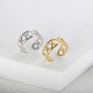 Detail of hollow heart-pattern rings in silver and gold finishes with adjustable open band