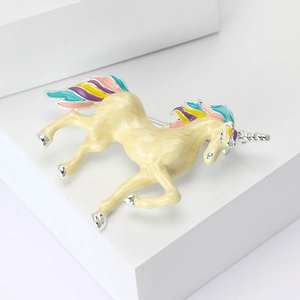 Enamel unicorn brooch with colorful mane on white geometric display stand