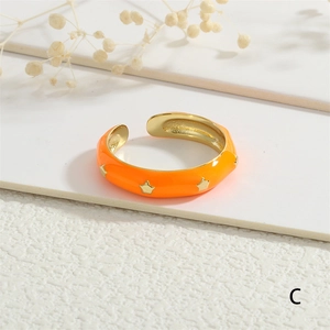 Macro detail of orange enamel star ring with 18K gold plating on textured surface