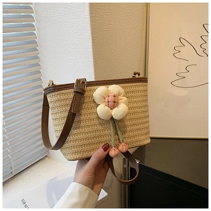 Detailed weave of beige straw tote with large floral accent and brown leather trim