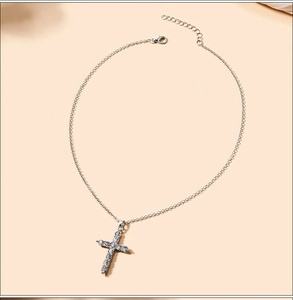 Macro shot of silver alloy cross necklace featuring sparkling rhinestone details and thin link chain