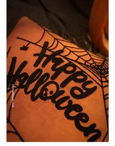 Detail of Happy Halloween embroidery on orange plush pillowcase with spider web and ghost