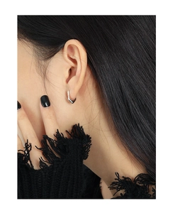 Detailed close-up of U-shaped silver earring featuring irregular hammered texture on model