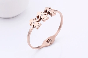 Detail of rose gold bangle featuring three girl charms with sparkling white zircons