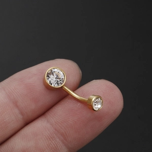 Navelpiercing van titaniumstaal met zirkonia kristallen vastgehouden tussen vingers