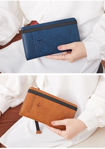 Close-up of passport wallet with elastic strap showing embossed logo and leather texture