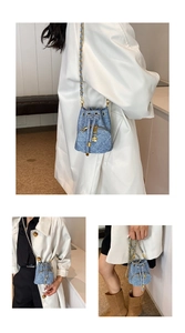 Macro shot of quilted denim bucket bag featuring golden chain strap and camellia charm