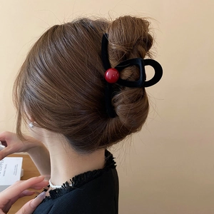 Close-up of black velvet hair claw clip with red bead on an elegant bun hairstyle