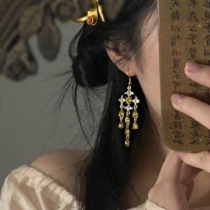 Macro shot of vintage star drop earrings with crystal tassels on a female model