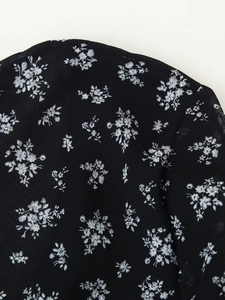 Détail du tissu en mousseline florale sur une robe à col en V profond et volants