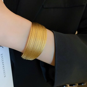 Dettaglio del bracciale rigido dorato a più strati con trama a spirale e finitura lucida