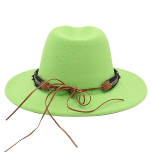 Detail of bright green fedora hat with black woven band and brown leather strap accent