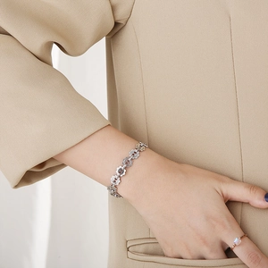 Detailed view of silver gear-link bracelet on model wrist with minimalist ring
