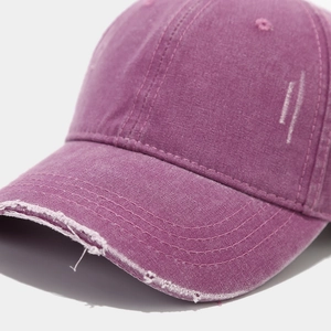Close-up of distressed brim on purple washed cotton baseball cap with vintage finish