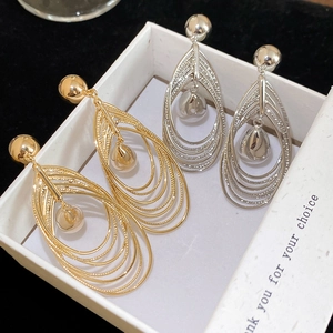 Detailed macro view of 18k gold and silver layered teardrop earrings with central pearls