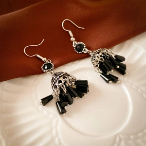 Detailed view of vintage silver-tone tassel earrings with black beads on silk fabric