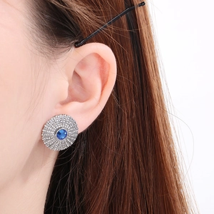 Detail of round sapphire-style titanium ear studs with sparkling diamond halo on ear