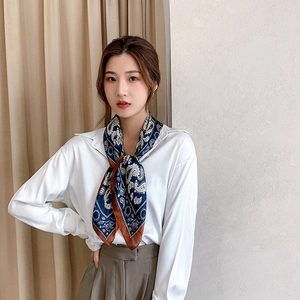Close-up of deep blue paisley silk scarf styled elegantly around a woman's neck