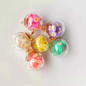 Detailed close-up of 16mm glass globes with colorful flower charms and gold metal loops