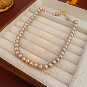 Detail of French vintage pearl necklace with golden clasp in a luxury wooden jewelry box