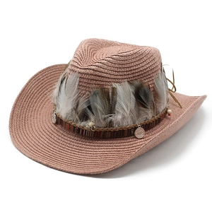 Detail of pink straw cowboy hat with ethnic woven band, feathers and metal coin pendants