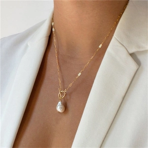 Detailed view of golden paperclip chain necklace with baroque pearl and T-bar clasp