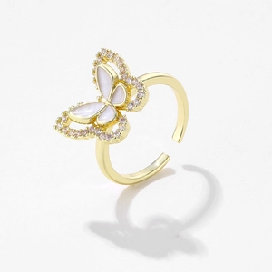 Macro shot of gold butterfly ring with shell inlay and purple crystals on white background