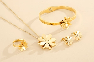 Detailed set of golden daisy necklace, bracelet, ring, and earrings on beige surface