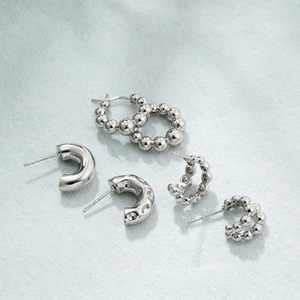 Detail view of silver C-shaped bubble ball earrings with smooth and textured finishes