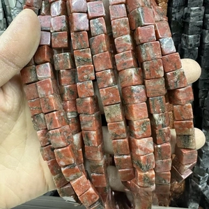 Détail de perles carrées en pierre naturelle aux textures minérales brun rouge et rose