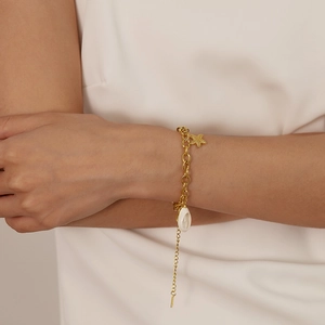 Detail of gold starfish and white shell pendants on a stainless steel chain bracelet