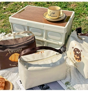 Detail of insulated lunch bags featuring cartoon prints on a grassy picnic setting