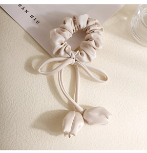 Detail of champagne satin scrunchie with tulip pendants and elegant silk-like ribbons