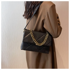 Detail van gewatteerde crossbodytas met gouden ketting en zwarte riem