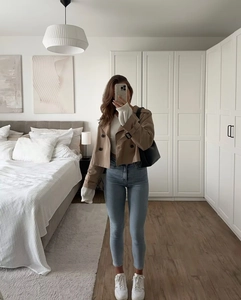 Mirror selfie showing a short khaki double-breasted trench coat with denim jeans
