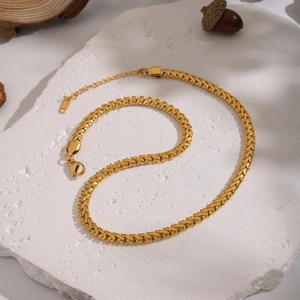 Gros plan d'un collier chaîne serpent en titane doré avec fermoir sur pierre blanche