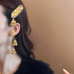 Detail view of gold ethnic hair clip with floral patterns and bells tassels on model