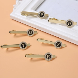 Detail view of round gold letter hair clips with rhinestones and black inlay for women