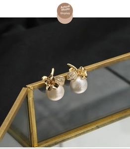 Close-up of pearl earrings with golden flower petals and shimmering zircon stone details
