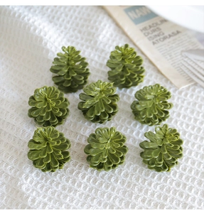Set of eight decorative green pine cones arranged on white mesh fabric for Christmas