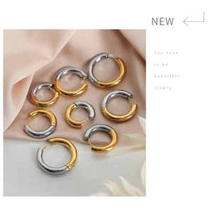 Macro shot of two-tone gold and silver stainless steel hoop earrings on pink silk cloth
