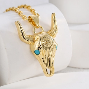 Detail of gold bull skull pendant with turquoise stone eyes in Western tribal style