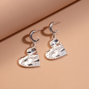 Detailed view of silver heart-shaped dangle earrings with a unique hammered texture finish
