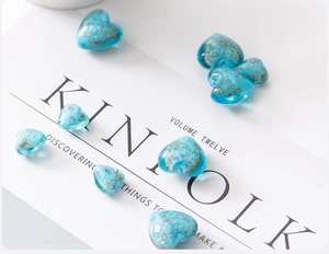 Close-up of heart-shaped blue glass beads with gold speckles for DIY jewelry making